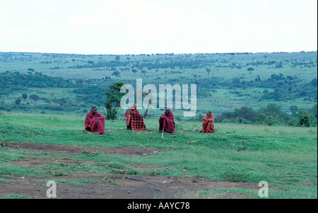 Kenia Masai Mara riserva nazionale Masai guerrieri in rosso tradizionale abbigliamento bovini di guardia in campo vicino il loro villaggio Foto Stock