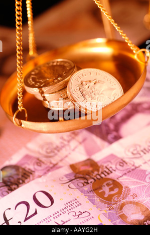 Pound monete in pan di bilance su banconote Foto Stock