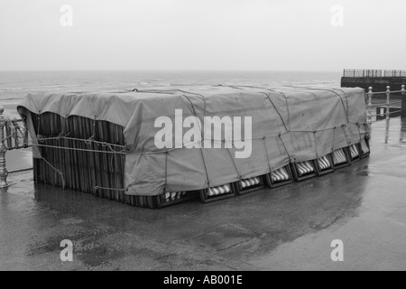 Sedie a sdraio legato sotto un telone sul lungomare di Blackpool sotto la pioggia Foto Stock