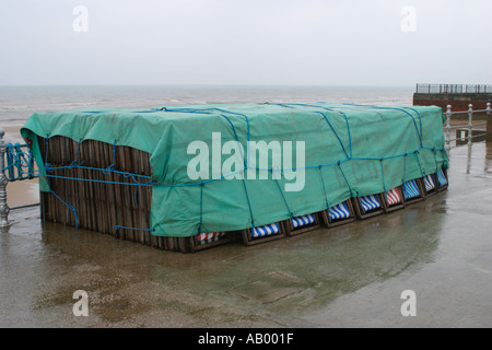 Sedie a sdraio legato sotto un telone sul lungomare di Blackpool sotto la pioggia Foto Stock