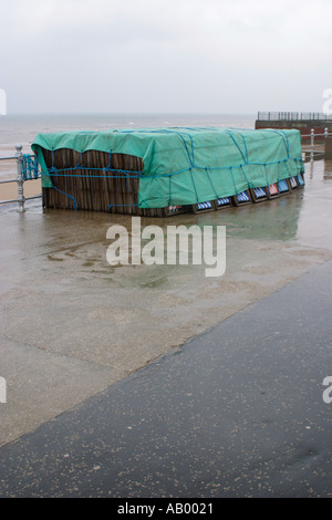 Sedie a sdraio legato sotto un telone sul lungomare di Blackpool sotto la pioggia Foto Stock