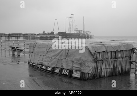 Sedie a sdraio legato sotto un telone sul lungomare di Blackpool sotto la pioggia Foto Stock