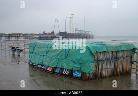 Sedie a sdraio legato sotto un telone sul lungomare di Blackpool sotto la pioggia Foto Stock