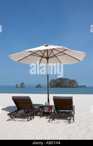Due vacante sedie a sdraio sotto bianco ombrellone sulla spiaggia di Tanjung Rhu Beach. L'isola di Langkawi, Malesia. Foto Stock