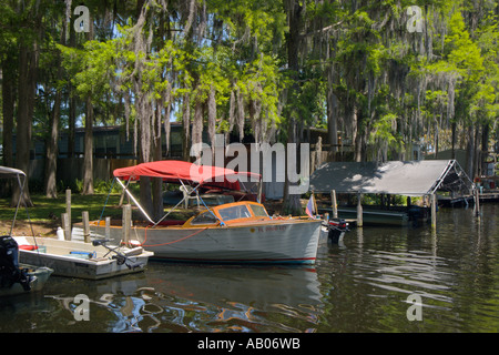 Barca in legno ancorata sotto cipressi con muschio spagnolo nel porticciolo del Lake Rousseau RV Resort vicino a Dunnellon e Crystal River, Florida, Stati Uniti Foto Stock
