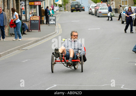 L'uomo sul triciclo recumbent nel centro della città di Hay on Wye Powys Wales UK Foto Stock