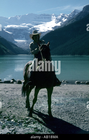 Cowboy Midnight: cavallo e cavaliere stagliano contro Rockies, Lago Louise, Alberta, Canada Foto Stock