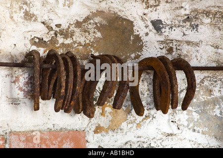 Rusty Ferri da cavallo appesi in una stabile Foto Stock