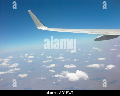 Ala piegata di aereo con una turbina in volo sopra le nuvole soffici Foto Stock