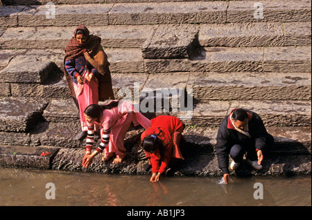 Fedeli al Ghats passi sulle rive di un fiume Kathmandu in Nepal Foto Stock