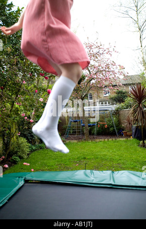 Ragazza saltando su trampolene in giardino Foto Stock