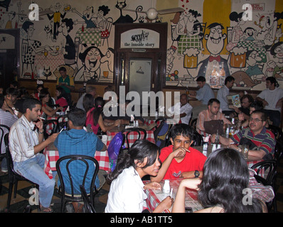 I clienti a popolare stile vecchio ristorante con muro di cartoni animati Cafè Mondegar Colaba Causeway Mumbai India Maharashtra Foto Stock