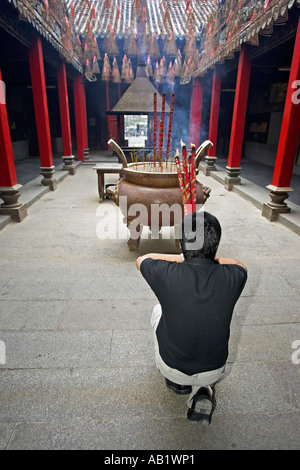 Uomo in ginocchio con grandi flaming bastoncini di incenso prega a Thien Hau signora del mare tempio di Ho Chi Minh City Vietnam Foto Stock