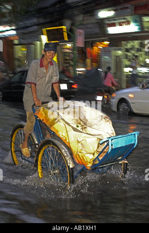 Il cyclo rickshaw driver pedali lungo allagato De Tham Street Pham Ngu Lao district Ho Chi Minh City Vietnam Foto Stock