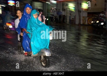 Uomo Donna e gioventù ride scooter lungo allagato De Tham Street Pham Ngu Lao district Ho Chi Minh City Vietnam Foto Stock