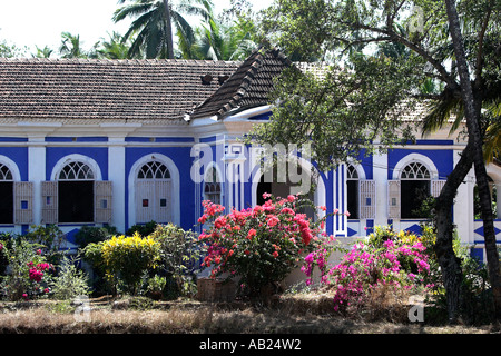 Attraente blu e bianco su un unico piano country house Casa Robello con ante e fiori tropicali Anjuna Goa in India Foto Stock