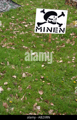 Segno di avvertimento di mine terrestri a terra a una ricreazione di un WW2 camp Foto Stock