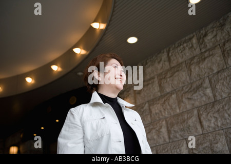 Senior donna in piedi nella parte anteriore dell'edificio Foto Stock