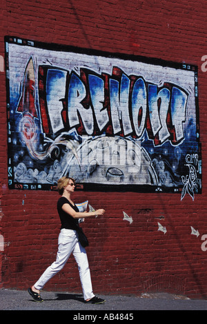 La donna a camminare lungo Fremont segno su edificio nel quartiere di Fremont Seattle Washington Foto Stock