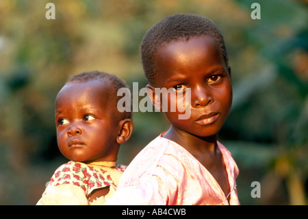 Triste guardando i giovani adolescenti ragazza locale che porta un bambino sulla schiena. Foto Stock