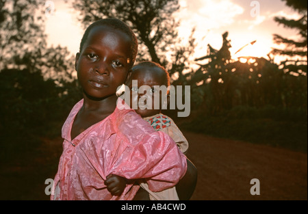 Triste guardando i giovani adolescenti ragazza locale che porta un bambino sulla schiena. Foto Stock