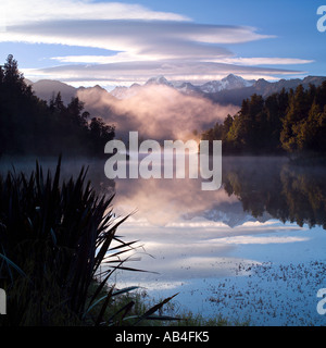 Golden mist rising all'alba dal lago Matheson, Nuova Zelanda Foto Stock