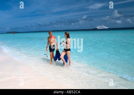 L'uomo e di una donna di ritorno da snorkeling su una bellissima spiaggia sandbank Bimathee Finolhu atollo di Baa Maldive Four Seasons Explorer Foto Stock