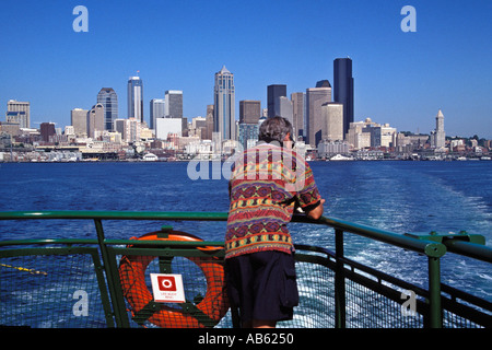 L uomo sta sul ponte di poppa della nave traghetto sul Puget Sound con Seattle Washington skyline a distanza Foto Stock