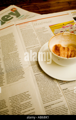 Un mezzo ubriaco tazza di cappuccino in appoggio sul quotidiano Guardian in un cafe, REGNO UNITO Foto Stock