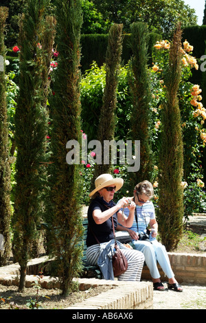 Donne di mezza età in rilassante giardino vestito in estate casual abiti e cappelli di paglia. Gli europei Foto Stock