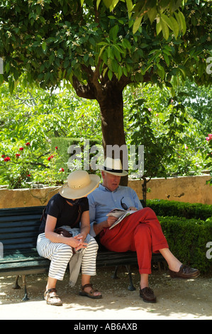 Coppia di mezza età rilassante sotto un albero vestito in estate casual abiti e cappelli di paglia. Gli europei Foto Stock