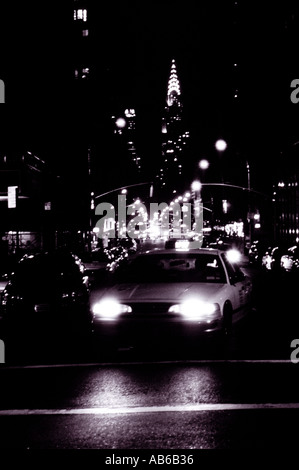 Taxi di notte con luci sfocate e Chrysler Building di New York City STATI UNITI D'AMERICA Foto Stock