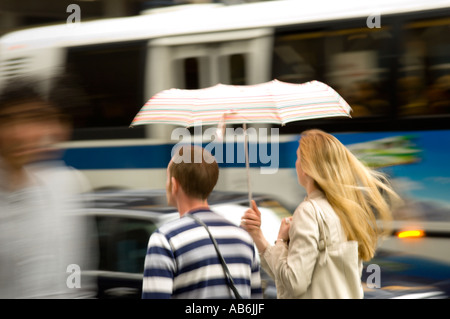 Giovane a piedi sotto la pioggia sotto ombrellone in città Foto Stock