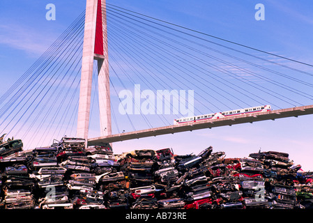 Lo SkyTrain attraversa ponte sopraelevato accanto a un Scrapyard di frantumato di vetture, New Westminster, BC, British Columbia, Canada Foto Stock