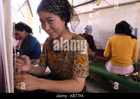 I lavoratori di sesso femminile in una tradizionale fabbrica di tappeti ad Hotan Xinjiang Cina lungo la Via della Seta Foto Stock