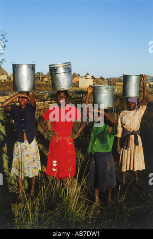 Giovani donne porting secchi di acqua nelle zone rurali dello Zimbabwe village Foto Stock