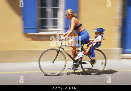 La madre e il bambino bike passato village casa in Provenza Francia blu su giallo Foto Stock