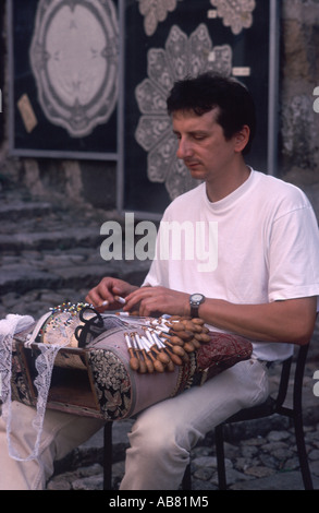 L'uomo facendo tradizionale merletto francese prima del suo negozio Le Puy-en-Velay, Haute Loire, Francia Foto Stock