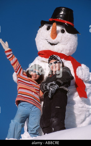 Due bambini di fronte a un pupazzo di neve artificiale, Francia Foto Stock