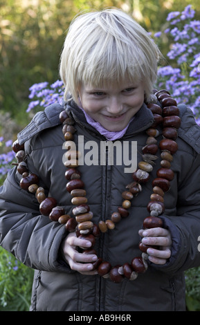 Buckeye, ippocastano (Aesculus spec.), i bambini a fare artigianato con castagne, ragazzo con una catena di castagne Foto Stock