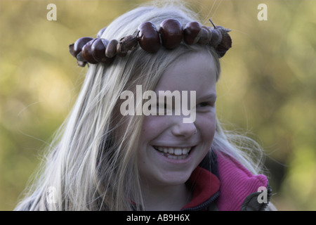 I bambini facendo handicarfts con castagne; ragazza con catena di castagno sul suo capo Foto Stock