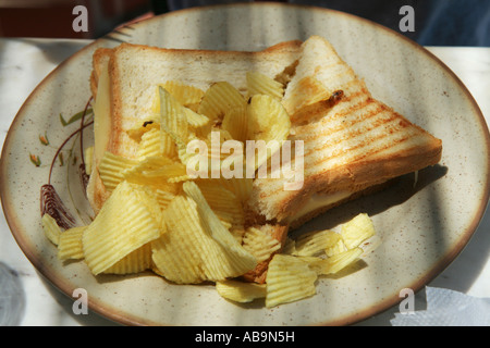 Una piastra con un prosciutto e formaggio toast doppia con chips patatine Foto Stock