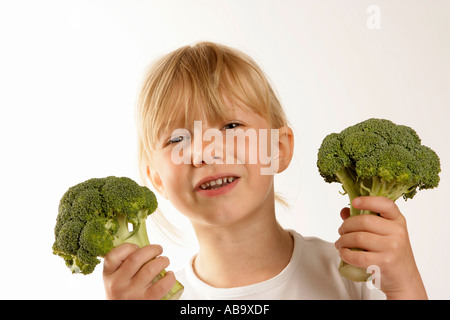 Ragazza giovane azienda broccoli che mostra un'espressione di antipatia Foto Stock