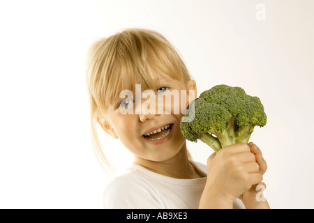 Giovane ragazza con un grande capo di broccoli Promozione di mangiare le verdure come parte di un helathy dieta bilanciata Foto Stock