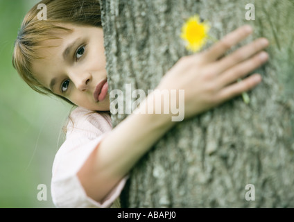 Ragazza con braccio intorno al tree, fiore di contenimento Foto Stock