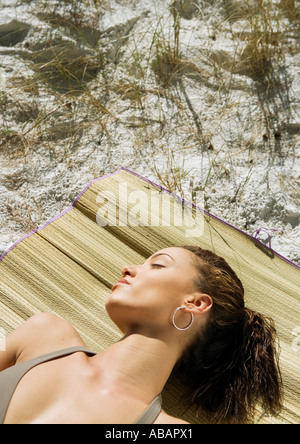 Giovane donna che dorme sul tappeto di spiaggia Foto Stock