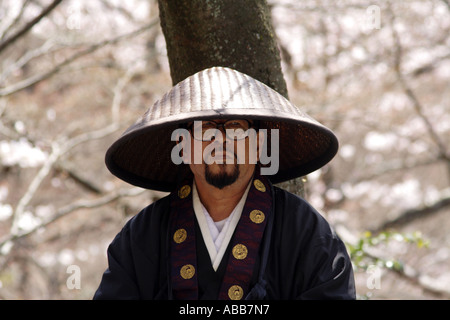 Uomo in Abbigliamento tradizionale e il cappello di fronte a pieno fiore fiori di ciliegio, Kyoto, Giappone Foto Stock