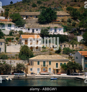 Sul lato del porto delle case sulla collina con un paio di barche ormeggiate sulla banchina di fronte Assos l'isola di Cefalonia le isole greche - Grecia Foto Stock