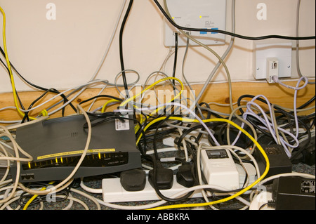Un groviglio di fili il computer sotto una scrivania in un luogo di lavoro Foto Stock