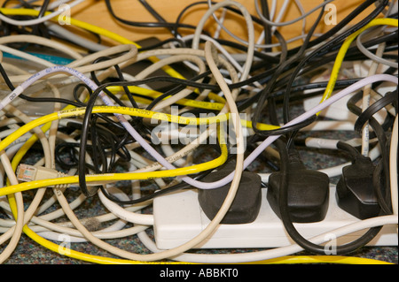 Un groviglio di fili il computer sotto una scrivania in un luogo di lavoro Foto Stock